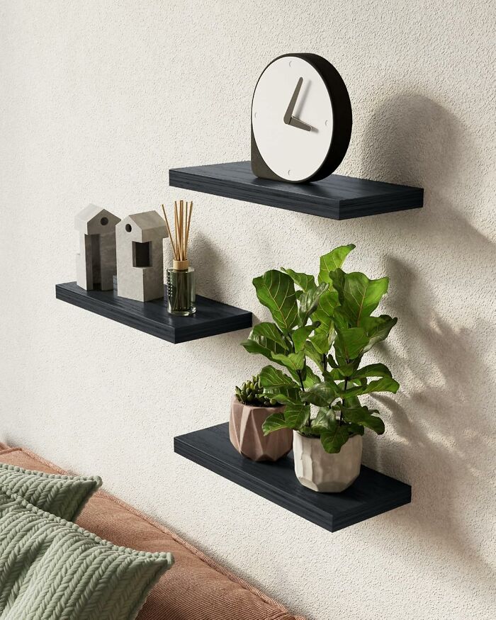 Floating black wall shelves with modern decor including a clock, small sculptures, diffuser, and green plants, Amazon finds.