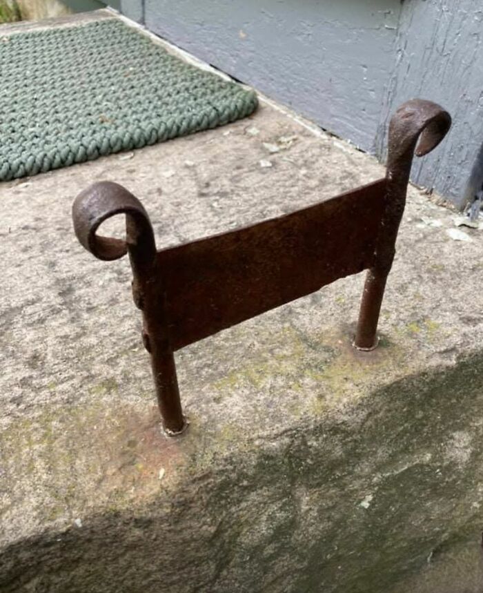 Rusty iron object with curled ends installed in a stone surface, one of the strange things found in homes with hidden pasts.
