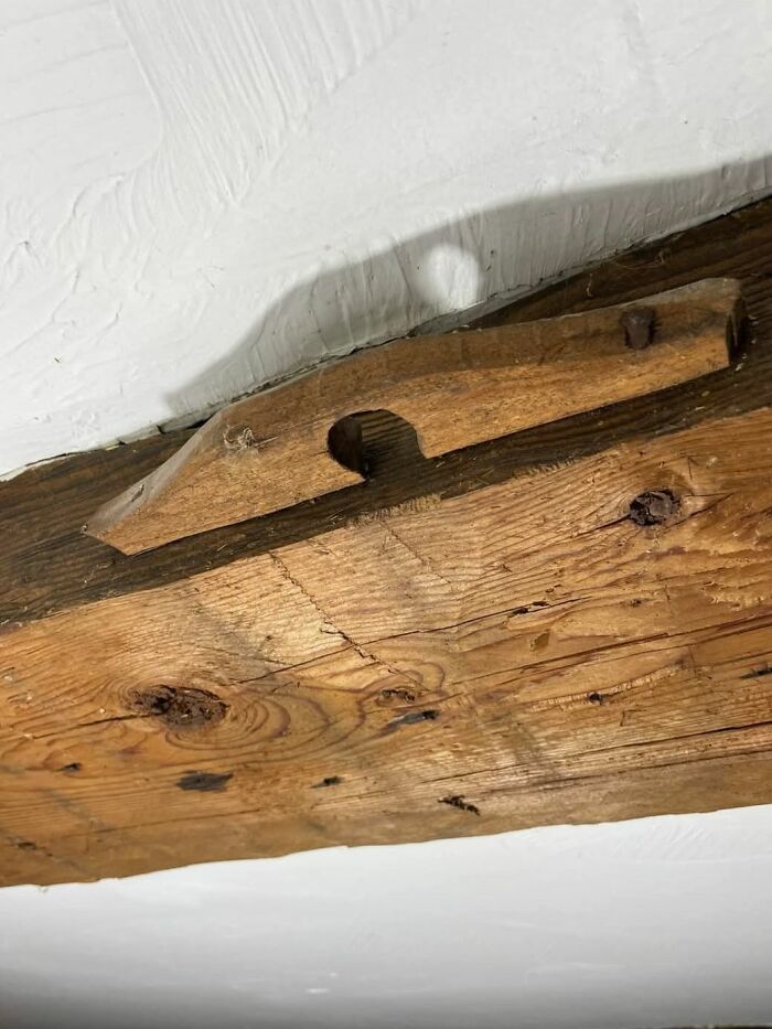 Old wooden object with nails on a rustic wooden beam inside a home with a hidden or forgotten past