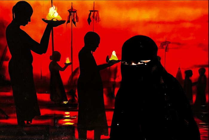 Silhouetted figures holding lamps against a fiery red background capturing pure street photography grant winners.