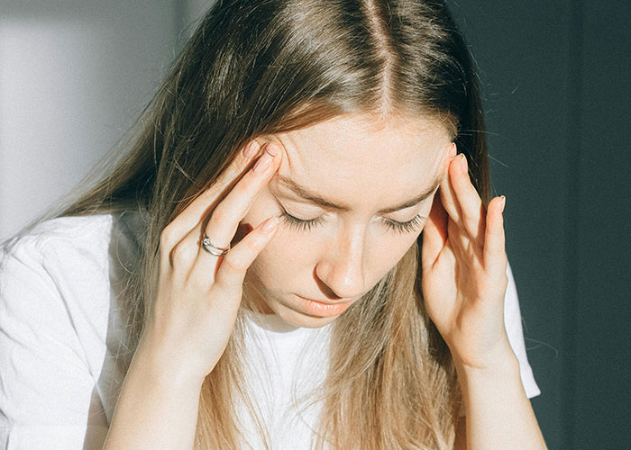 Woman holding her head in distress, reflecting trauma after being forced to hold a newborn by boyfriend.