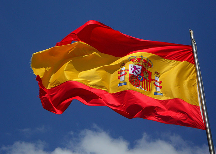Spanish flag waving in clear sky representing living in home countries and cultural experiences shared by 65 people.