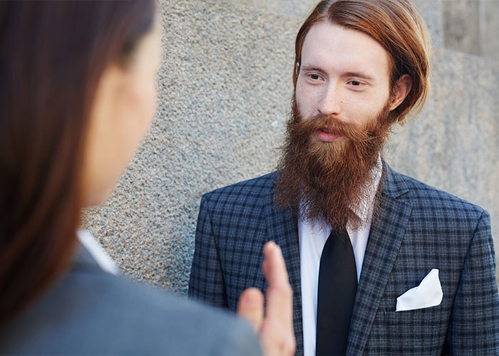 Two professionals discussing things everyone does but doesn’t talk about, dressed in business attire outdoors.