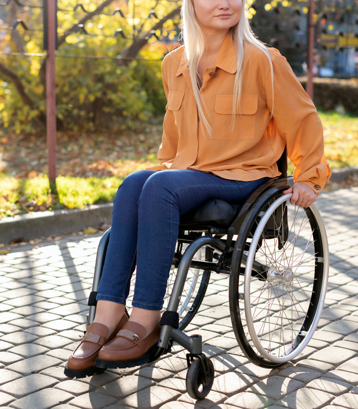 Woman with POTS in a wheelchair outdoors, highlighting invisible disability and challenges faced while using a car.