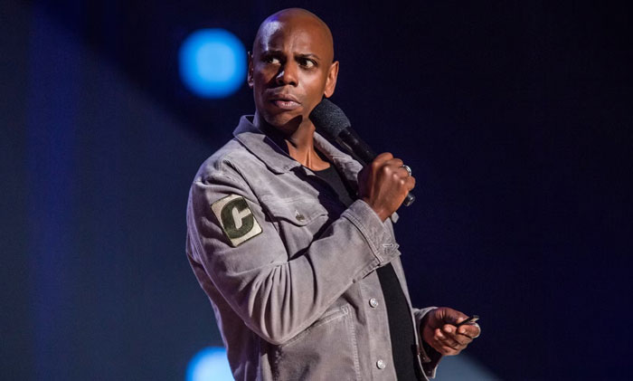 Comedian performing on stage holding a microphone, capturing a memorable celebrity encounter moment.