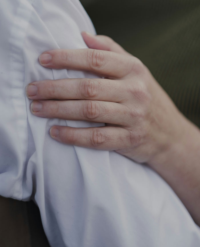Close-up of a hand resting on a white shirt, illustrating a moment related to weird parent rules in family life.