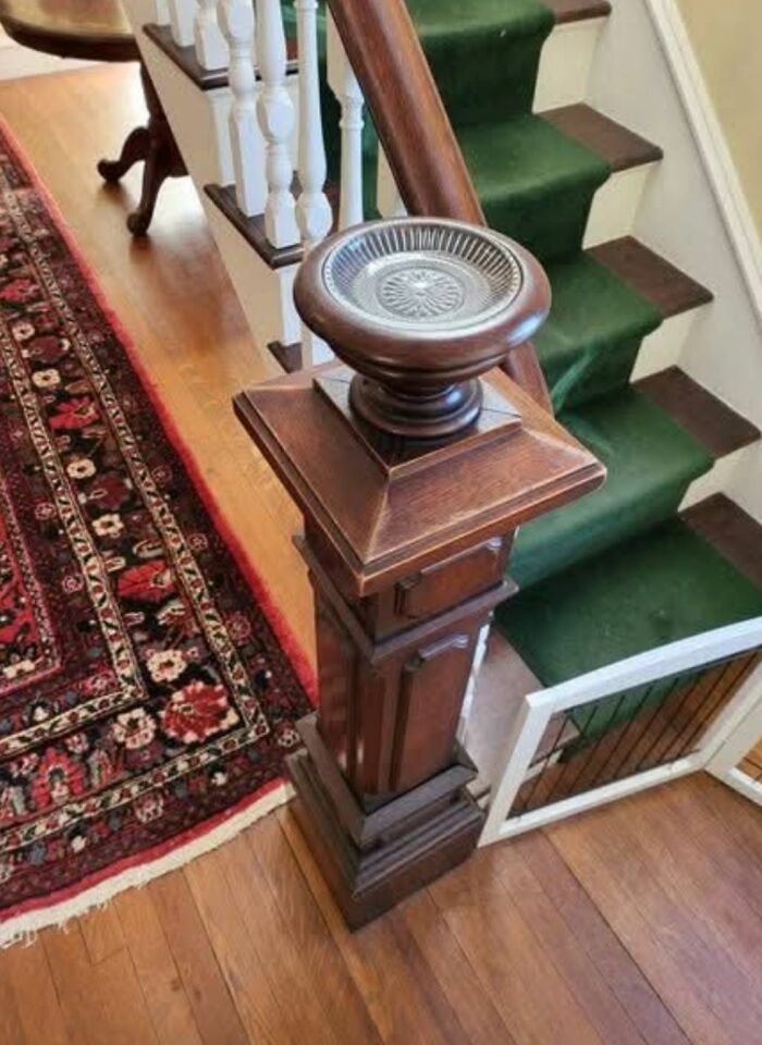 Ornate wooden newel post bowl feature on staircase in home with hidden and haunted past.