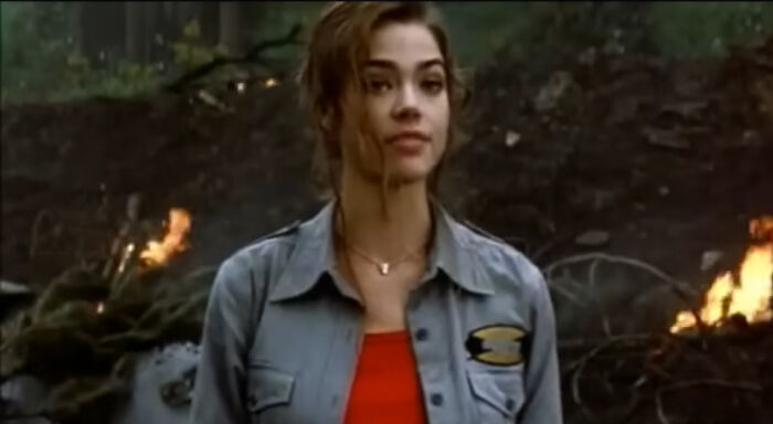 Actress in a forest scene with fires burning in the background, representing miscast actors in popular movies.