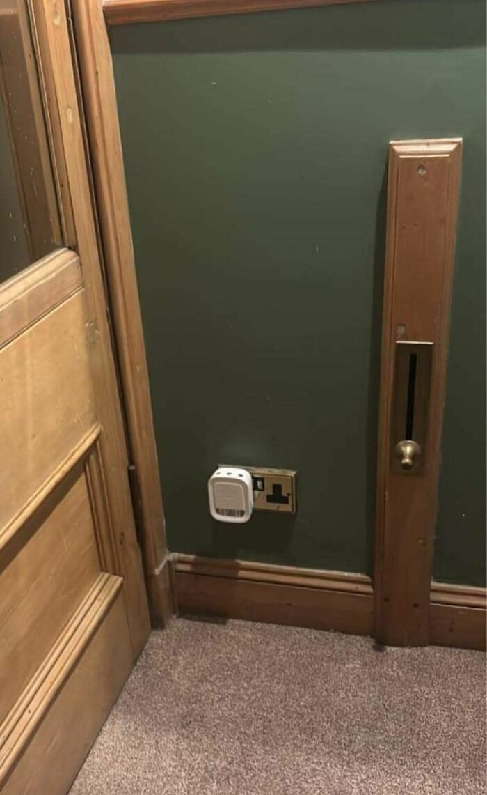 Old wooden door and wall with vintage electrical socket and unusual wall-mounted control in a home with hidden past.