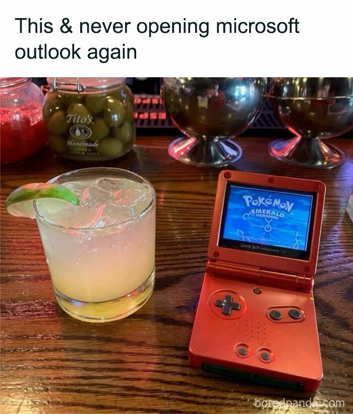 Retro handheld Game Boy playing Pokémon Emerald next to a cocktail on a wooden bar counter nostalgic ’90s meme.