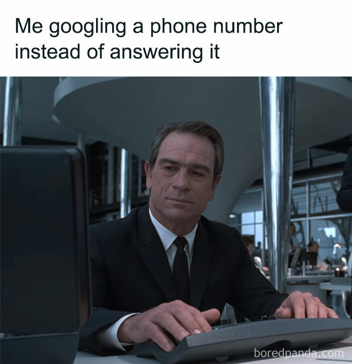 Man in a black suit at a computer, illustrating a nostalgic ’90s meme about googling phone numbers instead of answering calls.