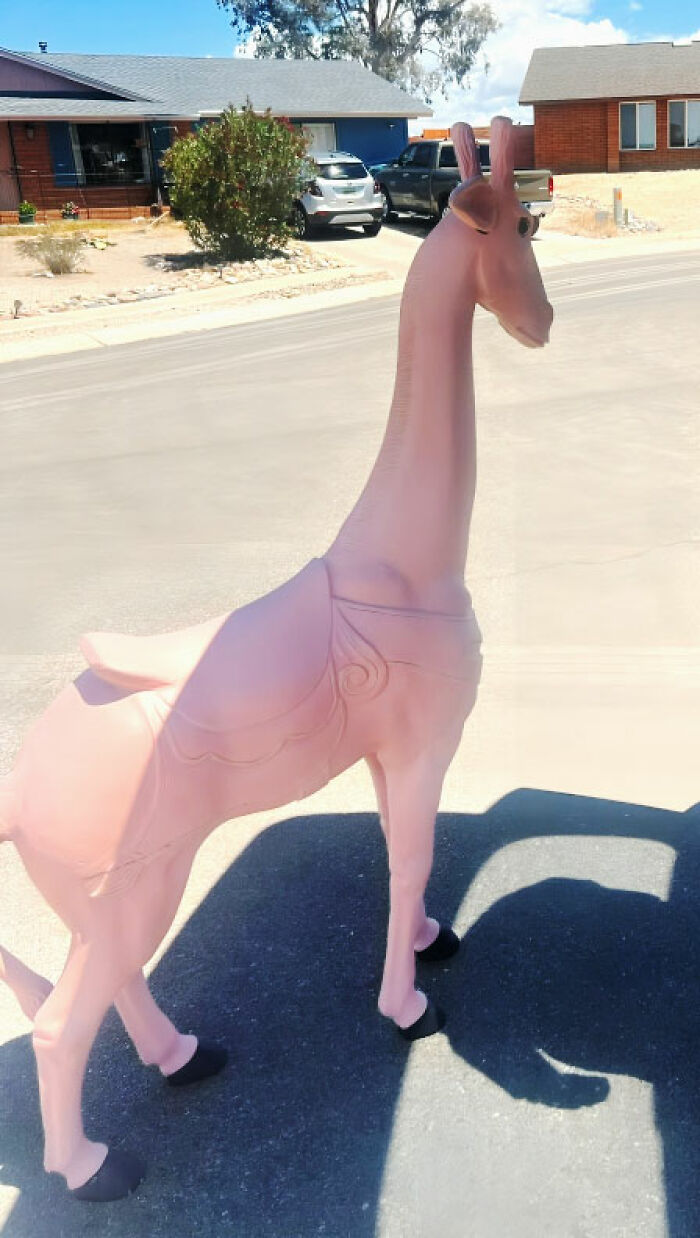 Pink giraffe statue with wings standing outdoors in a residential area among thrifted finds that are weird and wonderful