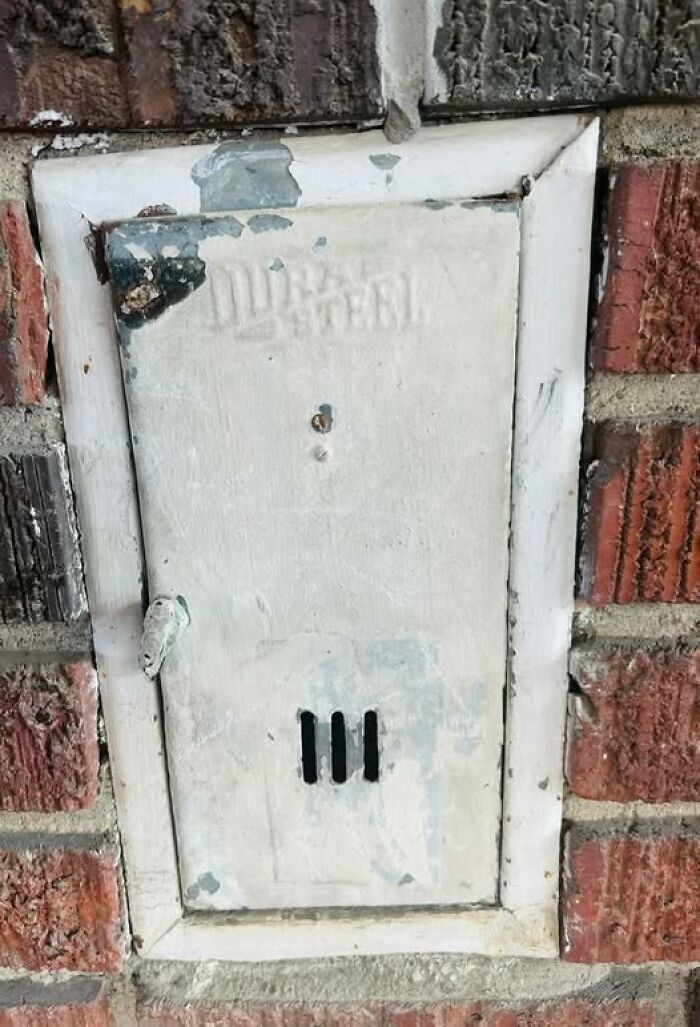Old metal box embedded in brick wall, a strange thing found in homes with hidden or forgotten pasts.