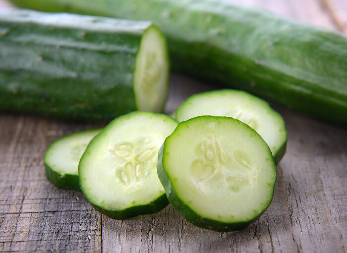 Fresh cucumber sliced on a wooden surface illustrating products requiring extra caution while cooking and eating.