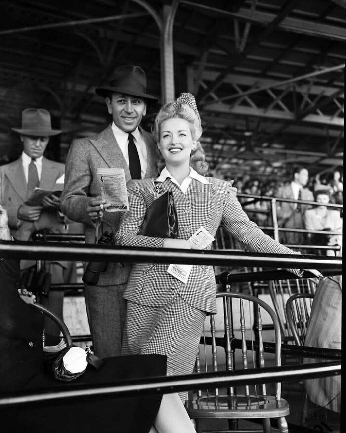 Black and white historic photo of a well-dressed couple at a stadium, showing an unseen side of history.