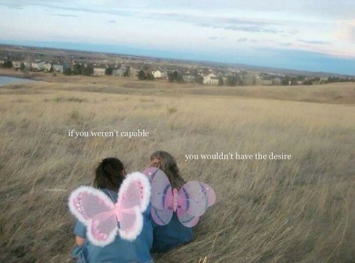 Two girls with butterfly wings sitting in a field, sharing cute and wholesome moments in a peaceful outdoor setting.