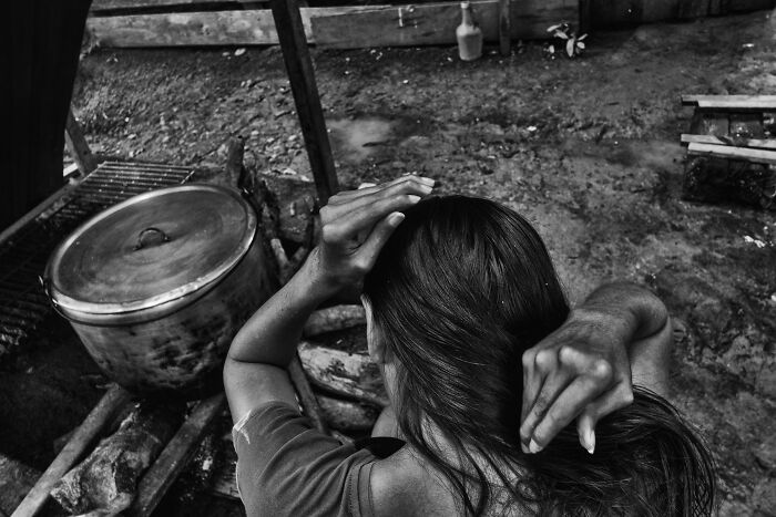 Black and white image of a person with long hair sitting outdoors, capturing the essence of humanity in IPA 2024 Best Of Show.