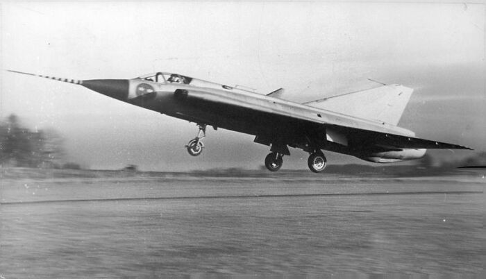 Vintage plane taking off from runway, showcasing classic aviation design and technology in black and white photo.