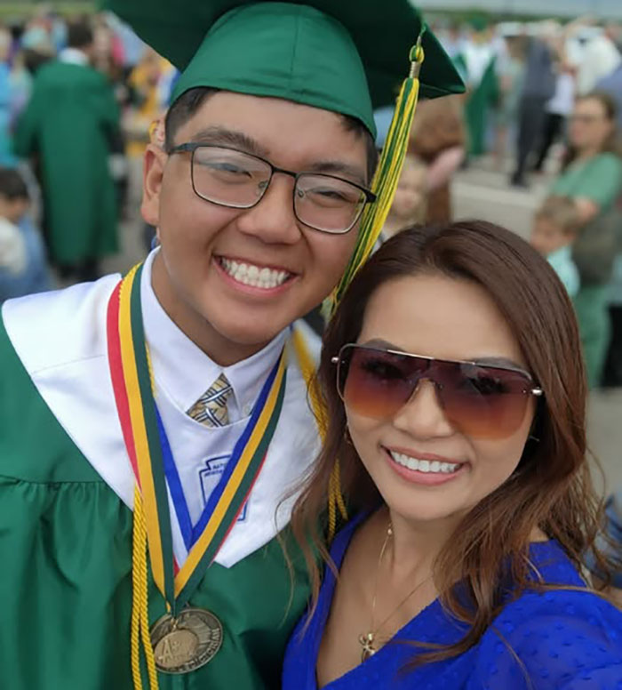 High school valedictorian in green cap and gown celebrates graduation with a woman amid controversy over speech and punishment.