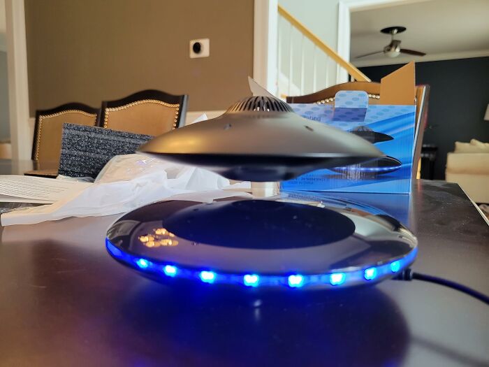 Levitating UFO-shaped gadget with blue LED lights on a table, showcasing innovative Amazon tech finds.
