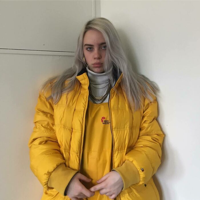 Young woman in a yellow puffer jacket and overalls posing indoors, reflecting iconic celebrity Instagram posts from way back in the day.