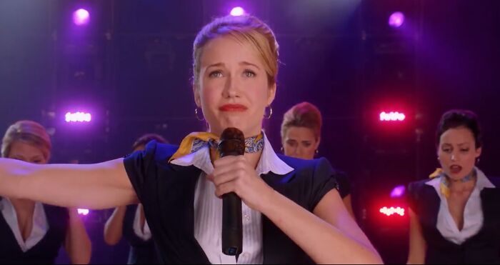 Actress performing on stage with backup dancers, representing horrifying behind-the-scenes facts from movies and TV.