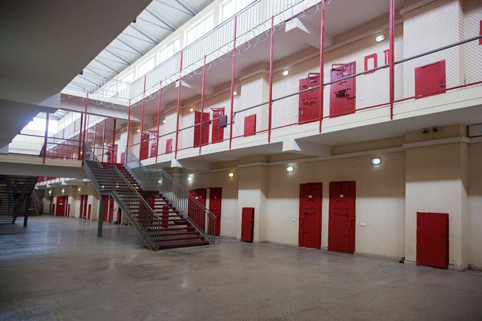 Prison interior with red secured doors and staircases, related to teen accused of smuggling in Thailand case.