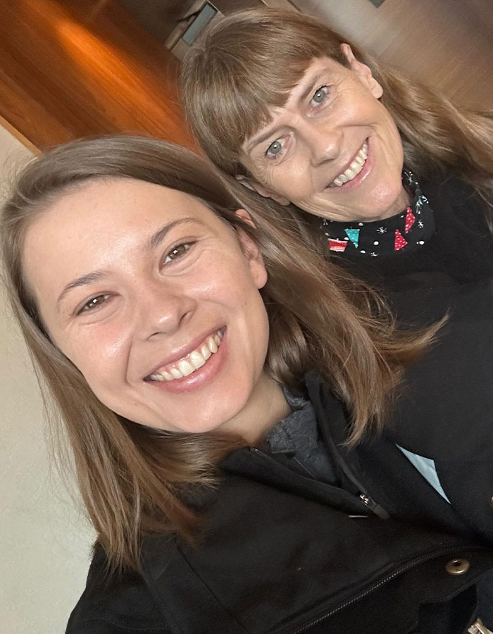 Bindi Irwin smiling with a woman indoors, sharing a health update from hospital after medical emergency due to incurable disease