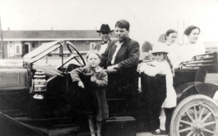 Black and white vintage photo of a family with children posing beside an old car, illustrating fascinating today I learned facts.