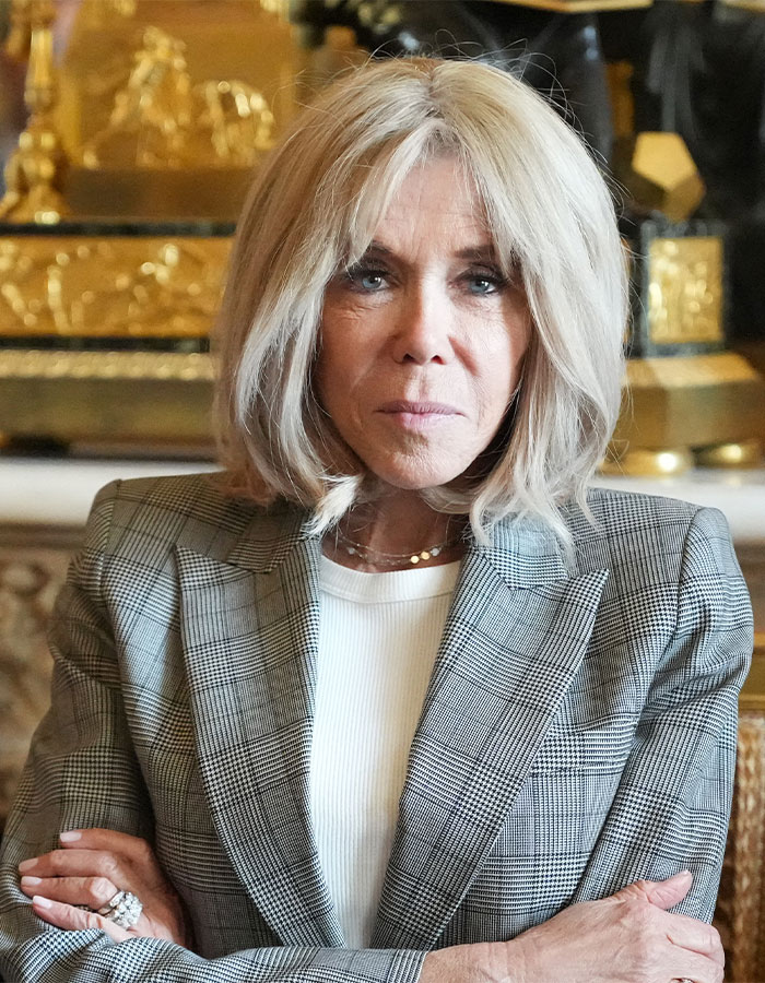 Brigitte Macron wearing checkered blazer indoors, related to Emmanuel Macron airport incident and grooming rumors. Brigitte Macron wearing checkered blazer indoors, related to Emmanuel Macron airport incident and grooming rumors.