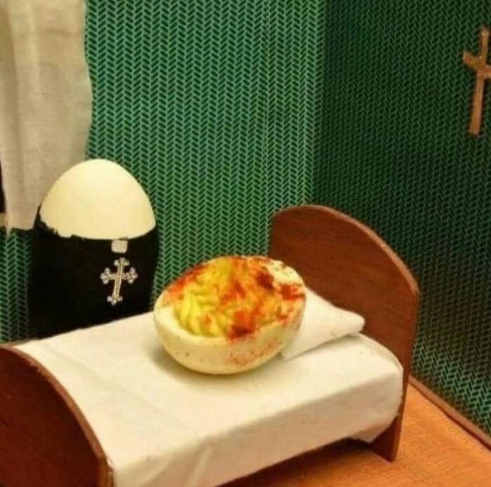 Relatable meme of a deviled egg in a bed with a figure dressed as a priest in a miniature room setup.
