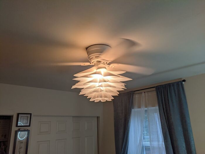Modern white ceiling light fixture illuminating a cozy bedroom, creating a happy place feeling at home.