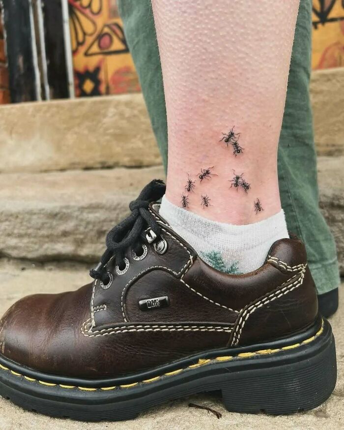 Tatuaje realista de pequeñas hormigas en tobillo junto a bota marrón en muestra de tatuajes graciosos y creativos.
