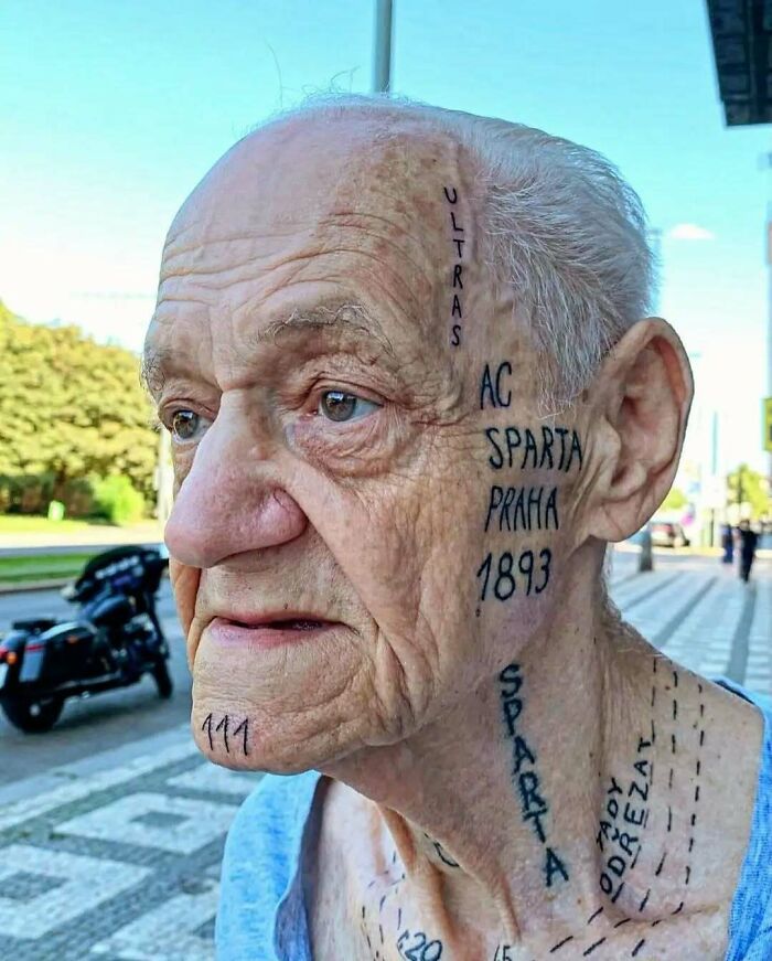 Elderly man with funny and interesting tattoos covering his face and neck, including text and numbers.