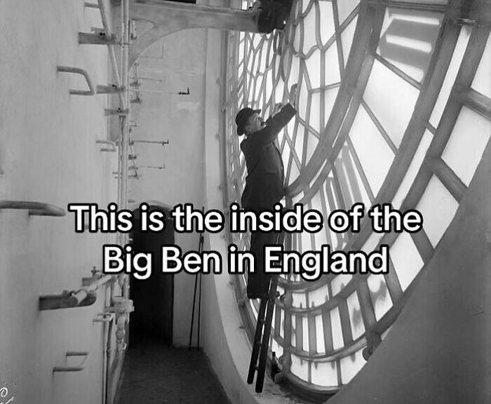 Man on ladder repairing the inside of Big Ben clock face, showing intricate structure and design details.