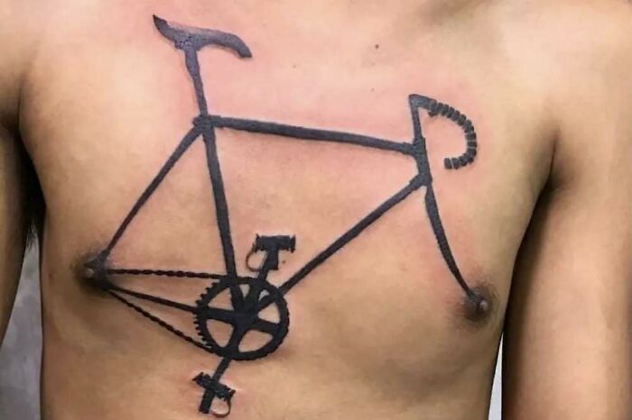 Chest tattoo of a bicycle with rough lines, showcasing one of the funny and bad tattoos on a bare torso.
