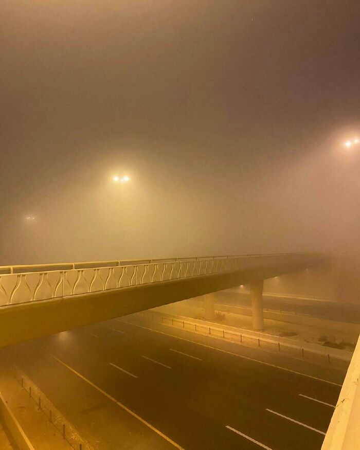 Empty space of an empty highway and bridge in heavy fog, creating an unsettling yet fascinating atmosphere at night.