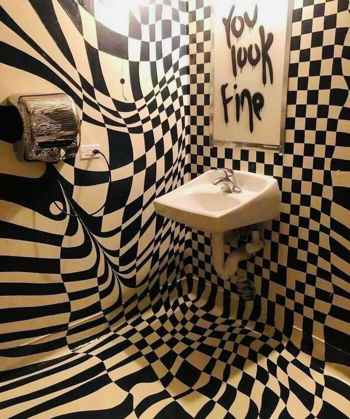 Bathroom with distorted black and white checkered walls and floor creating unsettling yet fascinating empty spaces effect.