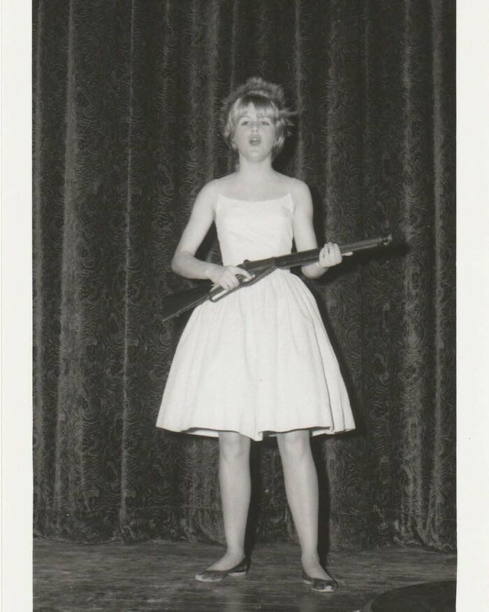 Young girl in a vintage photo holding a rifle on stage, showcasing interesting and mesmerizing history moments.