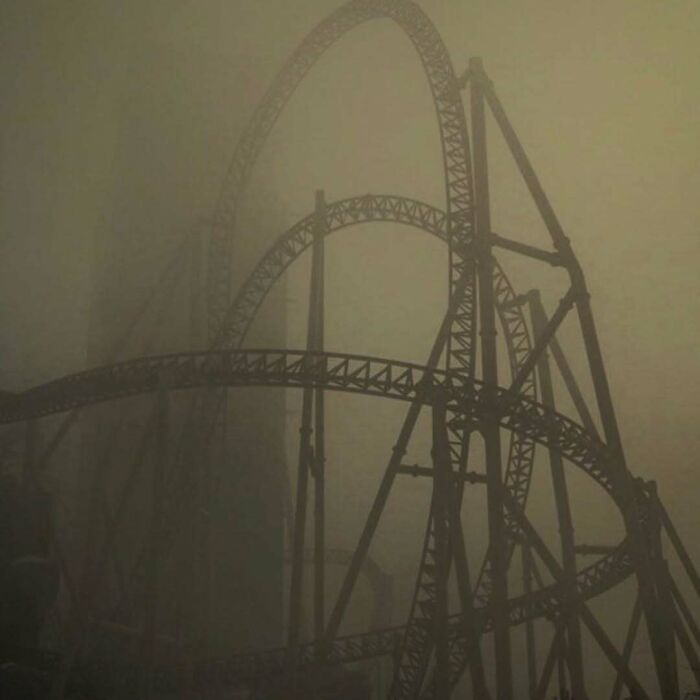 Roller coaster shrouded in thick fog, creating unsettling yet fascinating empty spaces in the eerie atmosphere.