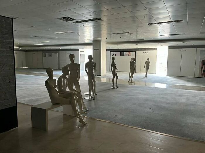 Empty mannequins in a large, vacant retail space creating unsettling yet fascinating empty spaces atmosphere.