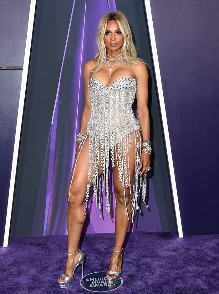 Woman wearing a revealing silver chain dress and high heels at the 2025 American Music Awards worst dressed stars event.