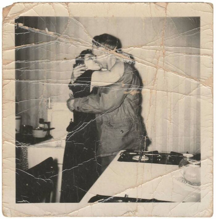 Vintage photo of a couple embracing and kissing in a kitchen showing a mesmerizing moment from history.