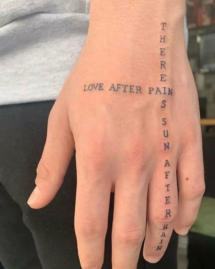 Tattoo on hand with vertical and horizontal text reading a confusing message, showcasing funny and interesting tattoos.