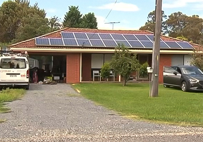 Suburban house with solar panels on roof, driveway with parked cars, related to woman sets childhood male friend on fire story.