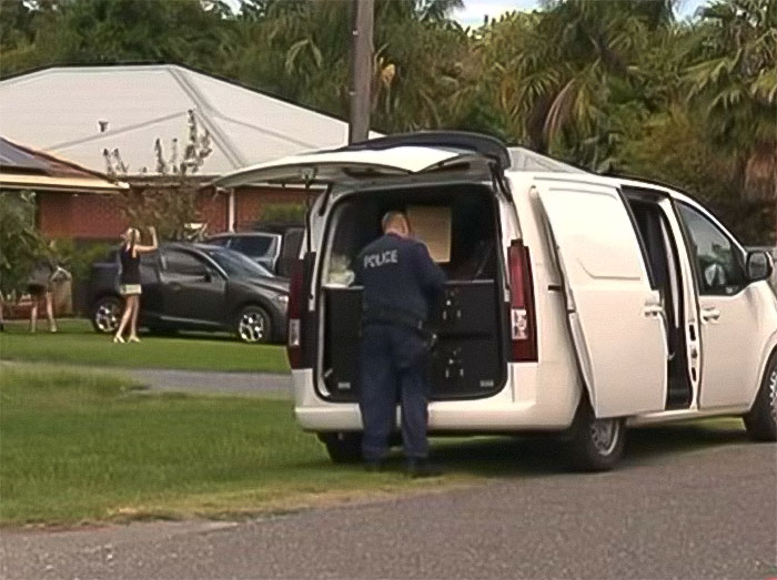 Police officer investigates outside a white van at a residential area after woman sets childhood male friend on fire incident.