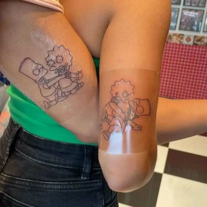 Tatuajes graciosos de Los Simpsons en los brazos de dos personas, mostrando diseño simple en líneas negras.