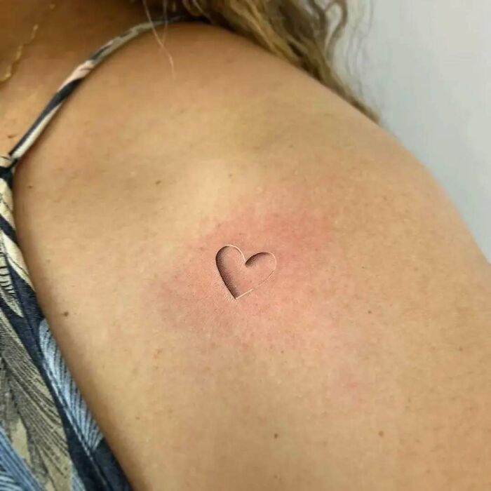 Tatuaje pequeño de corazón en brazo con diseño minimalista, ejemplo de tatuajes que van desde lo gracioso hasta lo terrible.