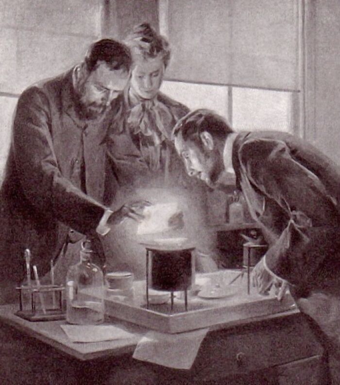 Vintage black and white image of Marie Curie and colleagues conducting scientific experiments in a laboratory setting.