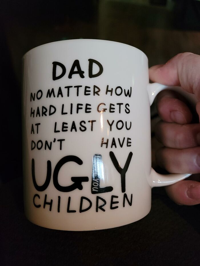 White coffee mug held in hand with humorous Father's Day gift quote about life and children, perfect gift idea.